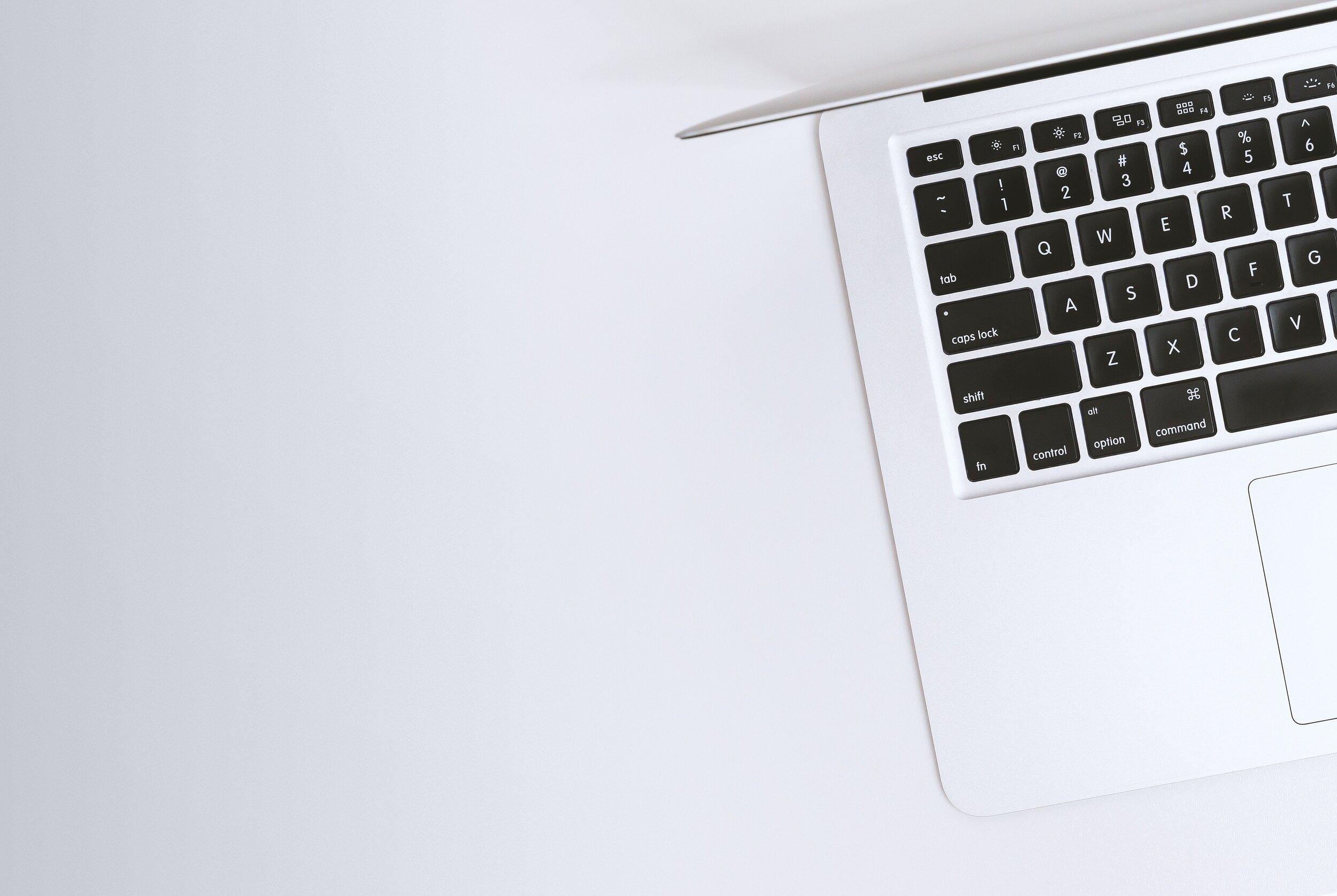 Overhead view of a MacBook laptop resting open on a white table.